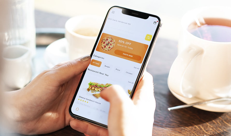 Hand of a person holding a cell phone while ordering a delivery